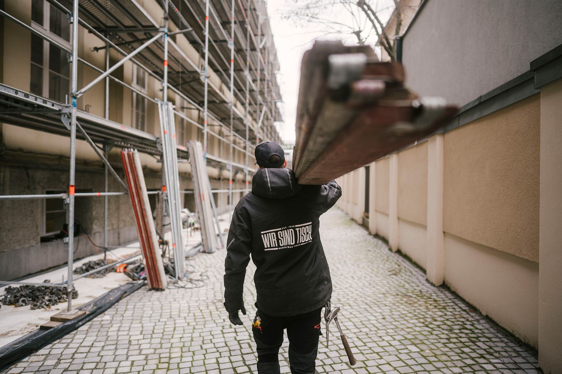 Gerüstbauer mit Tisch-Jacke auf der Baustelle
